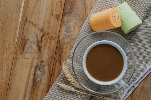 茶色の木の床に置かれたコーヒーとパン。