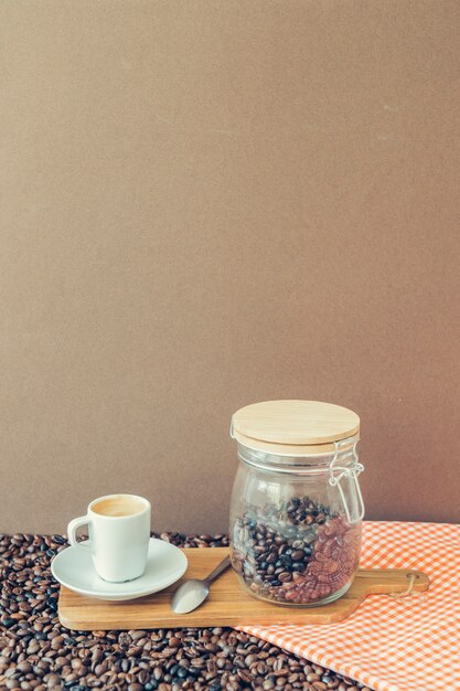 Coffee composition with cup and jar on wooden board