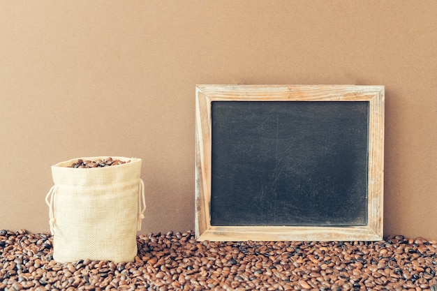 Foto gratuita caffè concetto con ardesia accanto a borsa riempito di chicchi di caffè