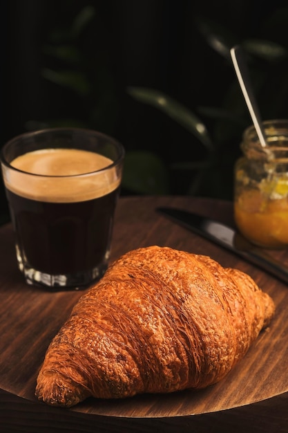 Кофейный круассан и джем на деревянном столе Французский завтрак в кафе Вертикальный снимок, выборочный фокус на круассан