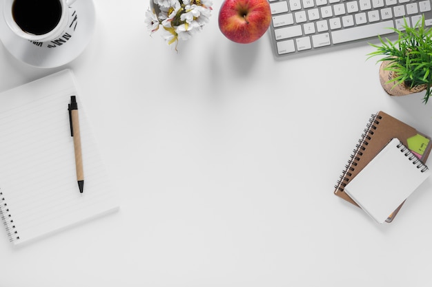 Coffee cup; apple and stationeries on office white desk