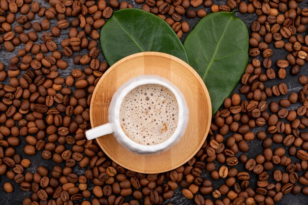 Coffee cup and coffee beans on black surface top view