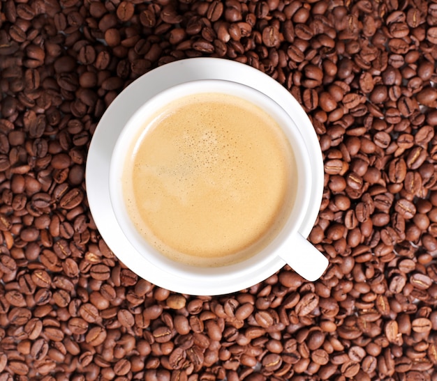 Coffee cup on coffee beans surface