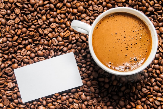 コーヒーカップとテーブル上のコーヒー豆、トップビュー、愛のコーヒー、白い背景に茶色のコーヒー豆、コーヒー豆とホットコーヒーカップ