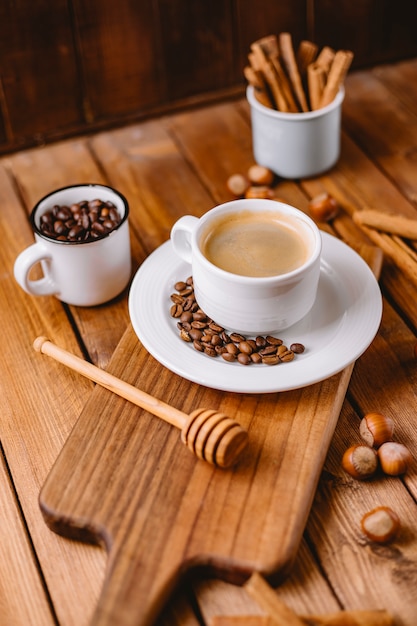 Coffee cup decorated with coffee beans placed on wooden serving board vertical