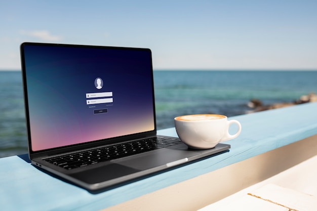 Foto gratuita tazza di caffè e laptop in riva al mare