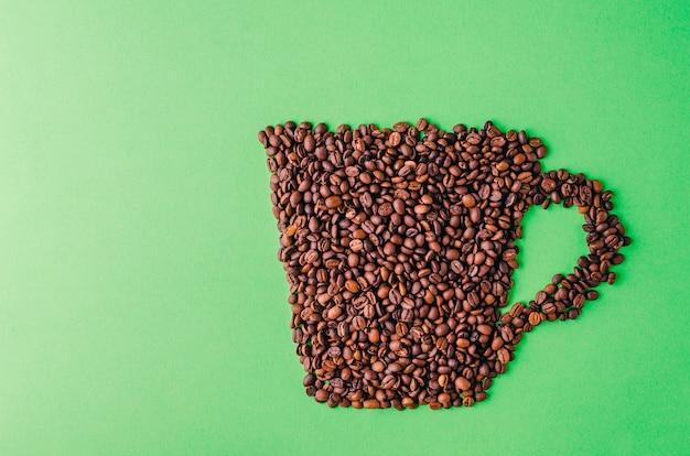 Free photo coffee cup made of coffee beans on a green background - perfect for a cool wallpaper