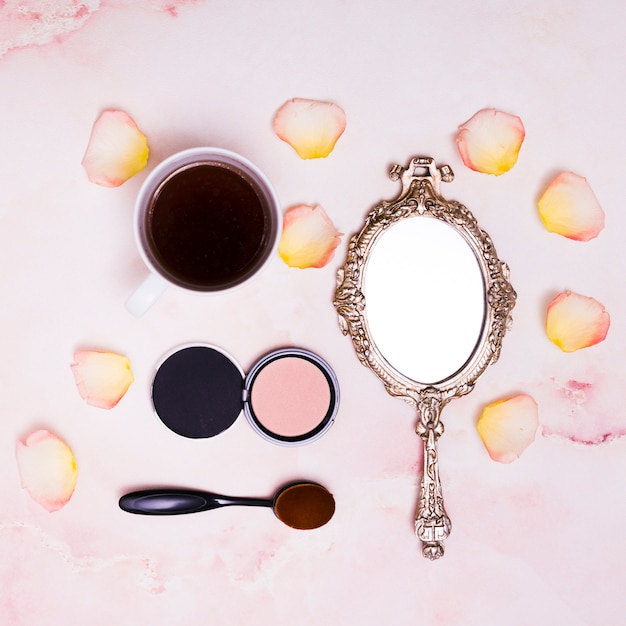 Coffee cup; petals; compact powder; oval brush and compact powder on pink background