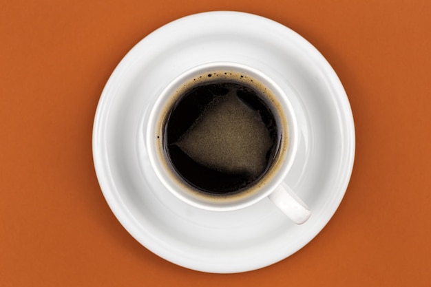 Foto gratuita tazza da caffè e piattino su sfondo marrone piatto