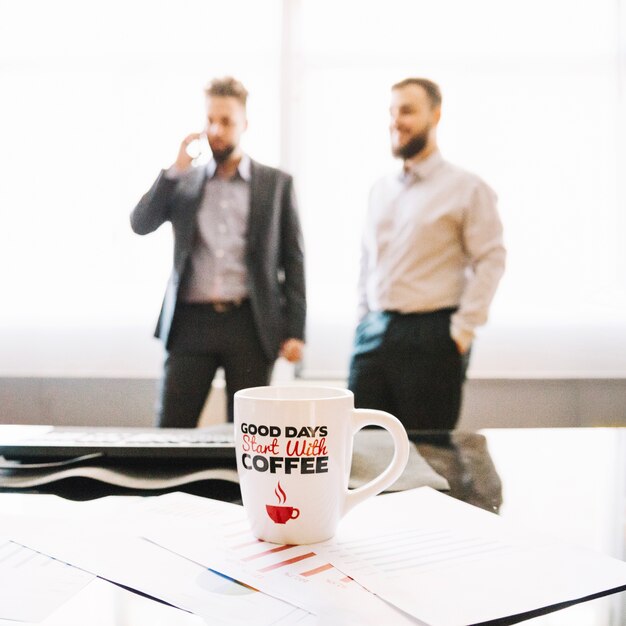 Coffee cup and two businessmen