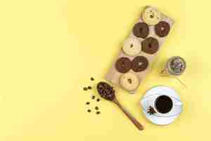 Free photo coffee in cup with coffee beans, biscuits, dried herbs on yellow background