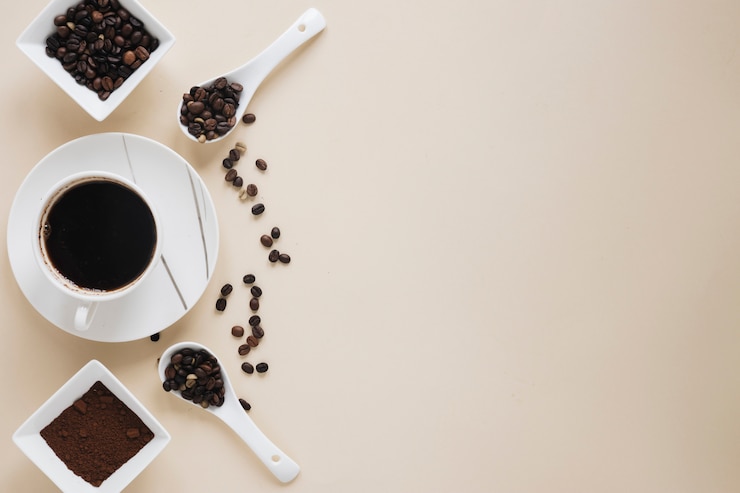 Free Photo coffee cup with coffee beans and coffee powder on beige background