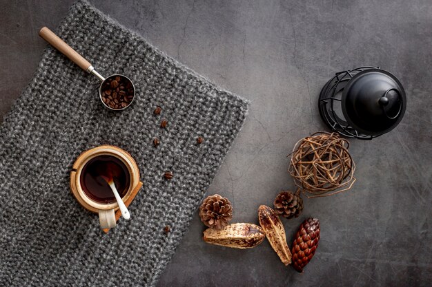 Coffee cup with coffee beans on a grey knitted scarf