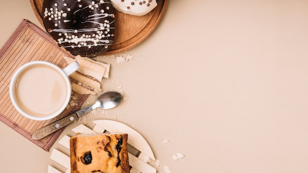 Coffee cup with donuts and pie on table