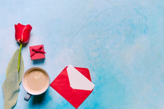 Coffee cup with red tulip on table 