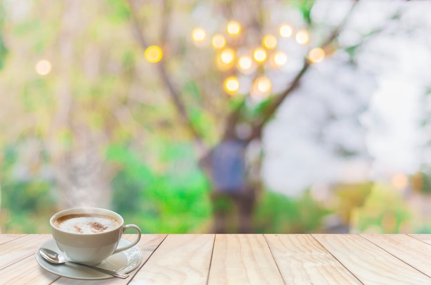 Coffee cup with smoke and spoon on white wooden terrace over blur light bokeh