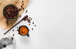 Coffee cup with strong espresso with foam, a coffee pot and coffee beans in a bowl