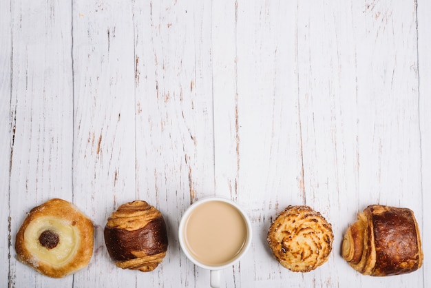 Foto gratuita tazza di caffè con panini dolci sul tavolo