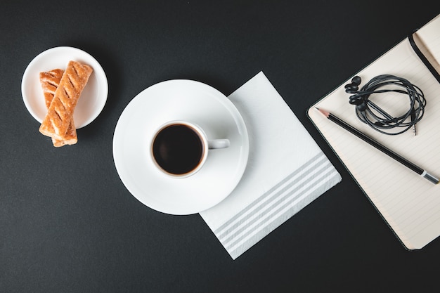 Coffee cup with sweets and notebook