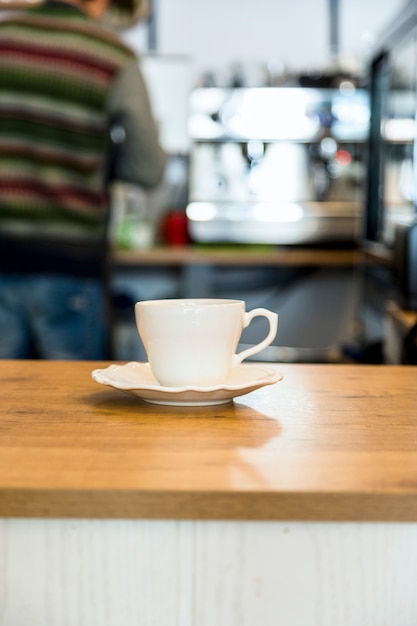 Coffee cup on wooden table over defocused cafeteria background