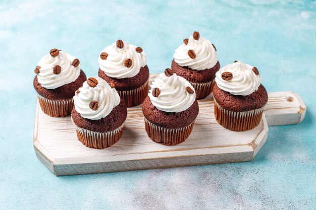 Coffee cupcakes decorated with whipped cream and coffee beans.