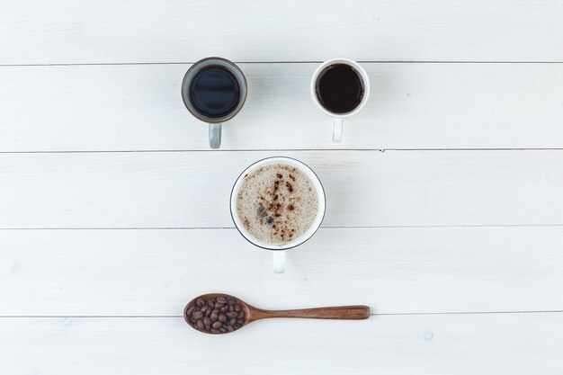 Кофе в чашках с кофейными зернами сверху на деревянном фоне