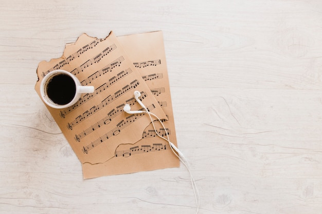 Coffee and earphones near sheet music