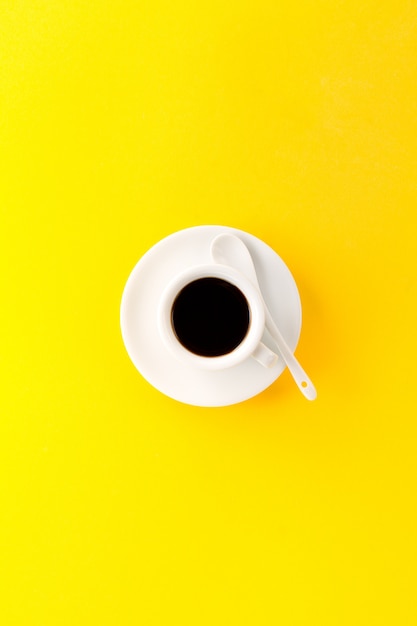 무료 사진 활기찬 노란색 배경에 작은 흰색 세라믹 컵에 커피 에스프레소. 미니 음식 아침 에너지 개념입니다.