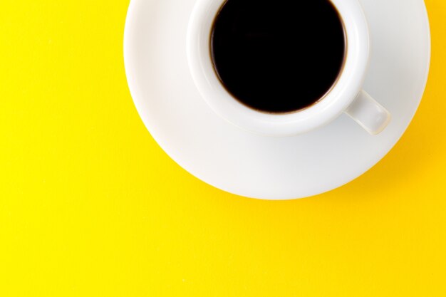 Кофе эспрессо в маленькой белой керамической чашке на желтом фоне. Минимализм Концепция концепции утренней энергии.
