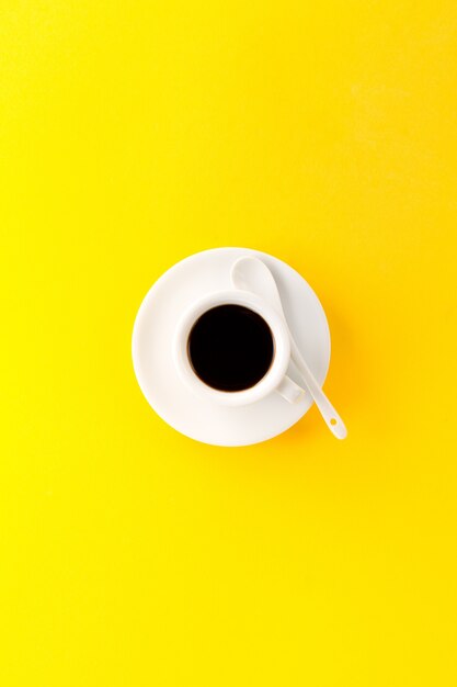 小さなエスプレッソ、小さな白いセラミックカップで、黄色の活気のある背景に。ミニマルフードモーニングエネルギーコンセプト。