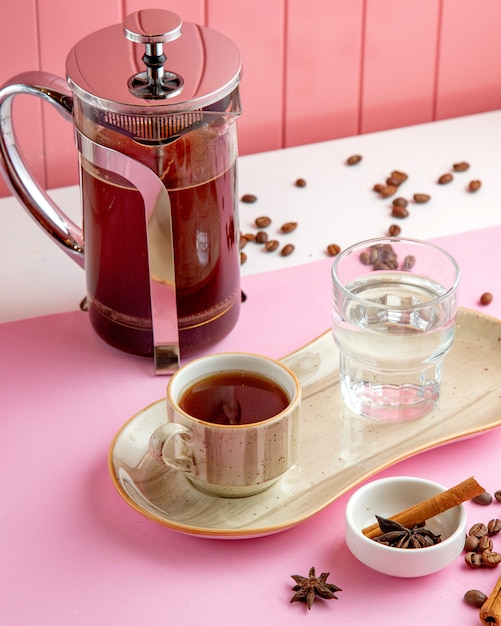 coffee in frech press glass of water and coffee beans on table