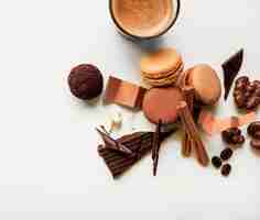 Free photo coffee glass; macaroons and chocolate piece with ingredients on white background