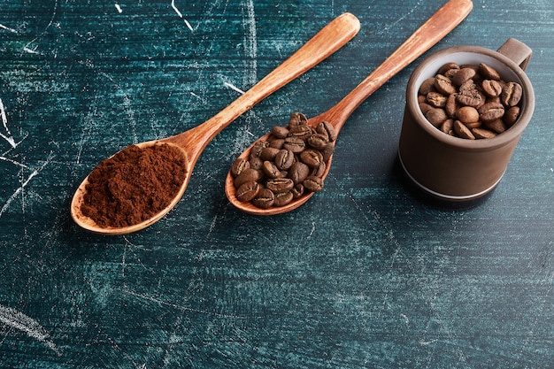 Coffee grains and powder in wooden spoons. 