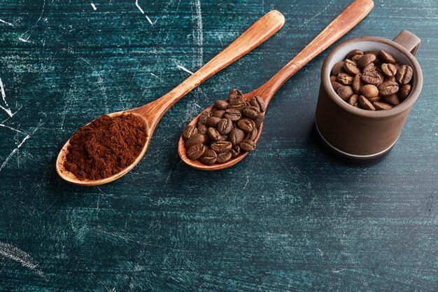 Coffee grains and powder in wooden spoons. 