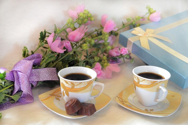 Кофе в чашке, конфеты, цветы и подарочная коробка