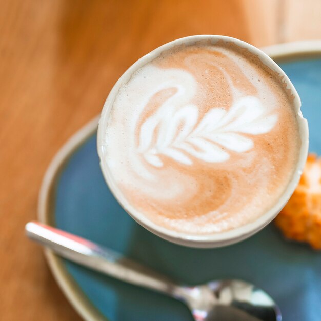 木製のテーブル上のカップでコーヒーラテアートカプチーノ泡