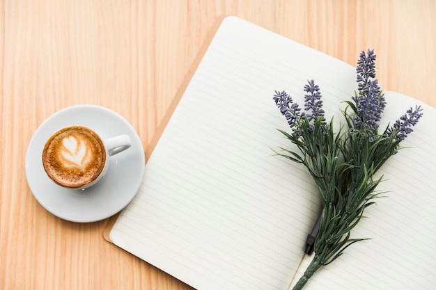Coffee latte,lavender flower and notebook on wooden desk