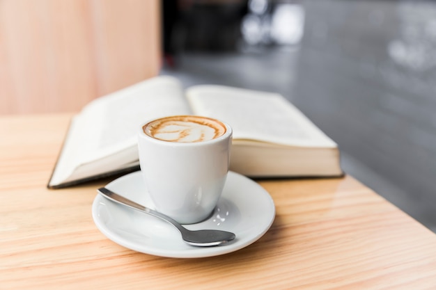 Coffee latte and open book on wooden desk