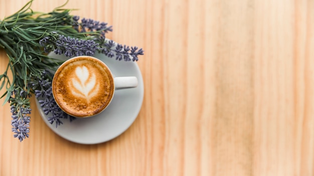 木製の表面にラベンダーの花とコーヒーラテ