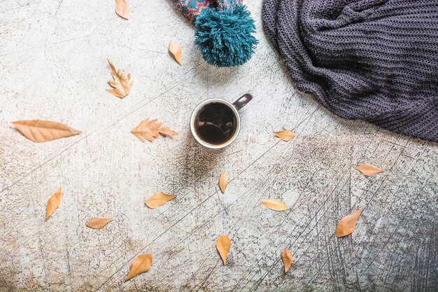 Coffee and leaves near hat and scarf