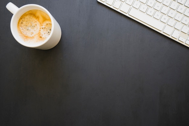 Free photo coffee mug an keyboard on dark desk