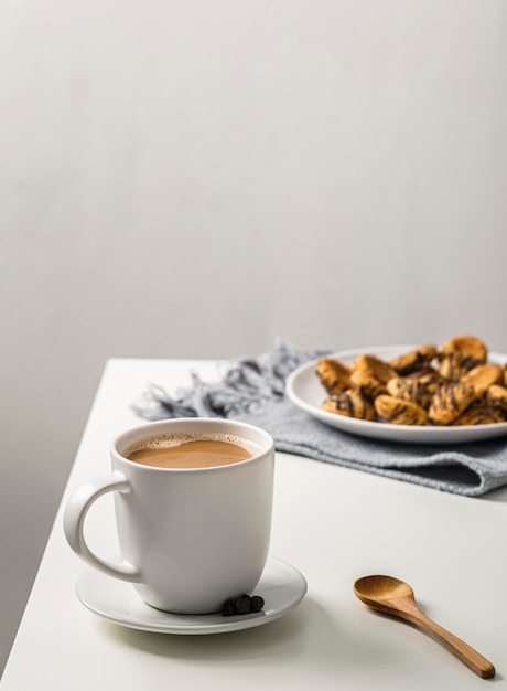 Coffee mug on table with plate of cookies