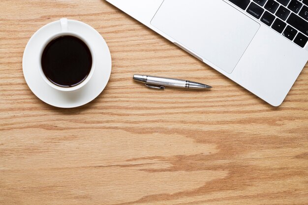 Coffee next to pen and laptop