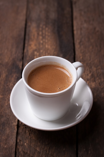 Coffee in porcelain cup on wooden table