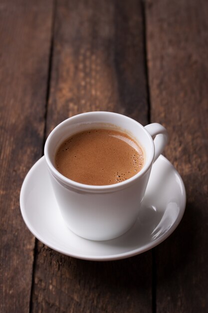 Кофе в фарфоровую чашку на деревянный стол