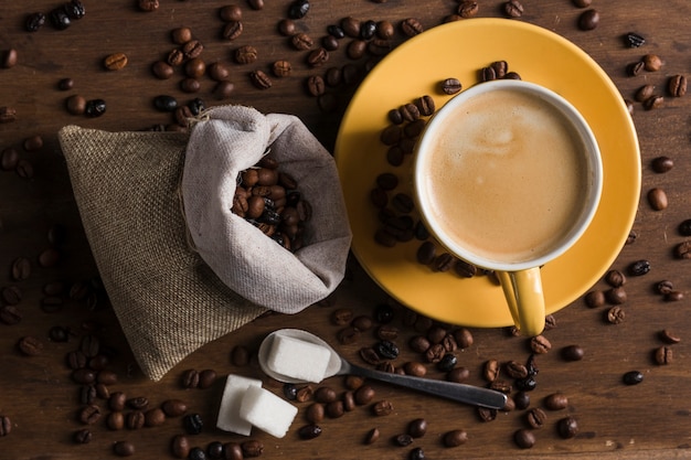 Set da caffè e zucchero sul cucchiaio vicino sacco di chicchi di caffè