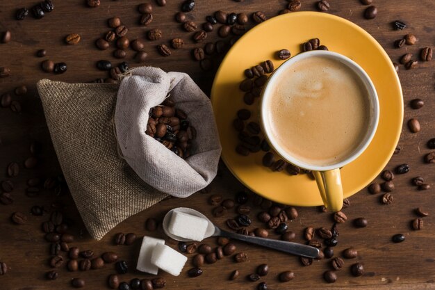 Coffee set and sugar on spoon near sack of coffee beans