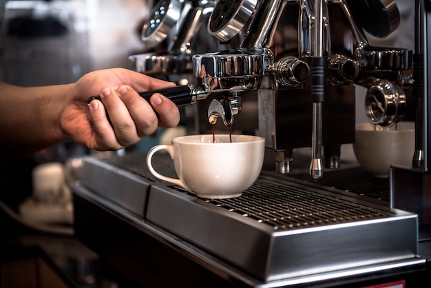 自動コーヒーマシンを使用している喫茶店のオーナーまたはバリスタは ビジネスと飲み物のコンセプトのために 濃縮されたコーヒー水を蒸留することによって働いています プレミアム写真 自動コーヒーマシンを使用している喫茶店のオーナーまたはバリスタは ビジネスと飲み物のコンセプトのために 濃縮されたコーヒー水を蒸留することによって働いています プレミアム写真