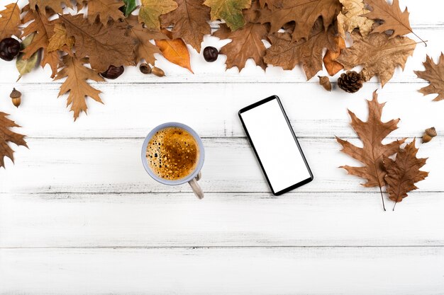 Coffee and smartphone layout on leaves background