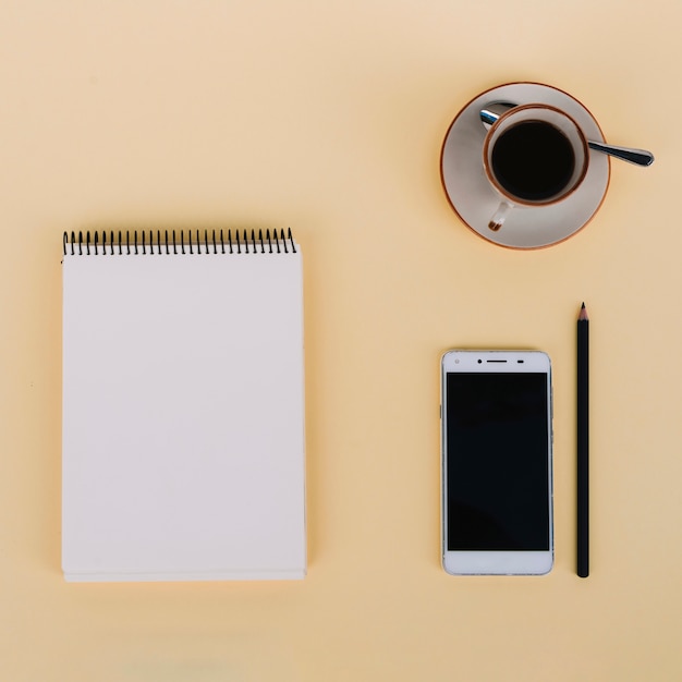 Coffee and smartphone near notebook